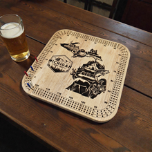 Load image into Gallery viewer, Wooden cribbage board with 'Michigan' design on a wooden table with a glass of beer.